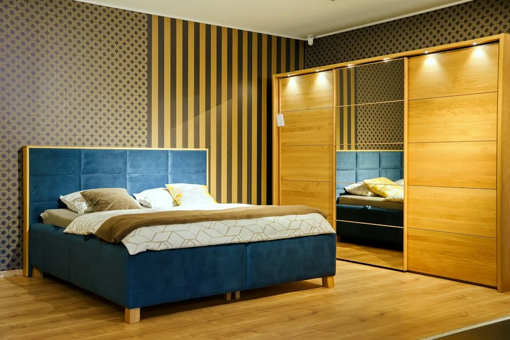 Made double bed with a blue upholstered headboard in a modern bedroom with a wardrobe