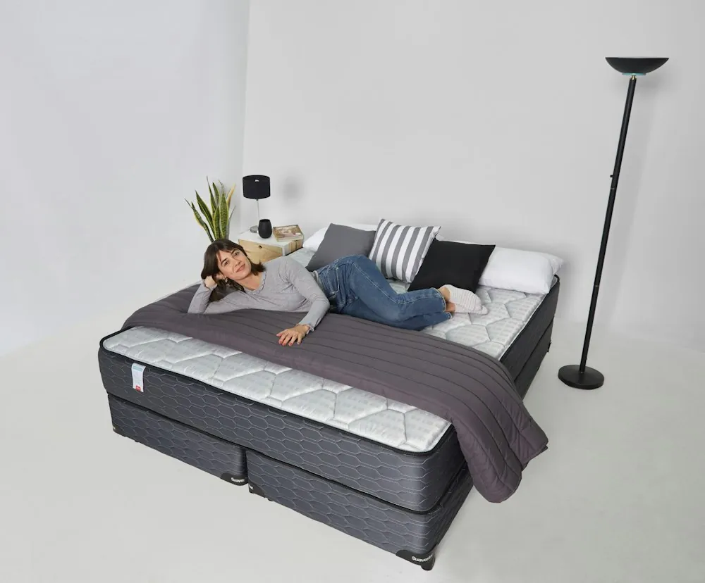 Person lying on their side on a mattress on a box base to test firmness and support